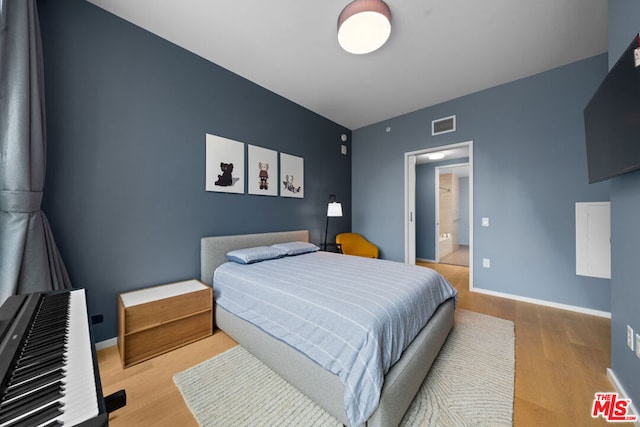 bedroom featuring ensuite bath and hardwood / wood-style floors