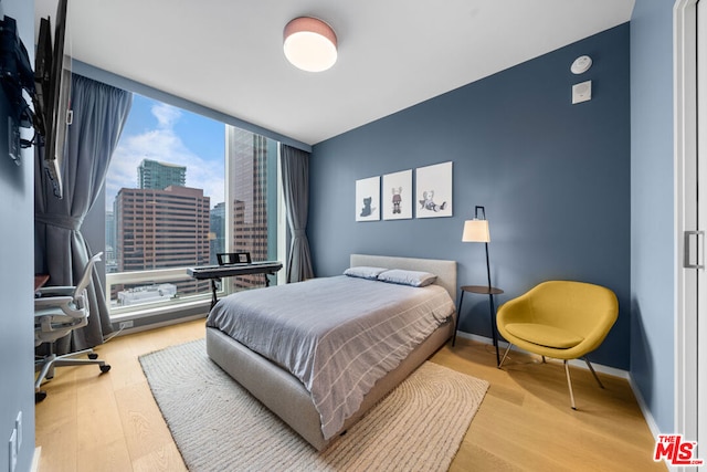 bedroom with floor to ceiling windows and light hardwood / wood-style flooring