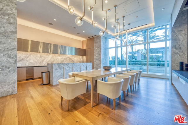 dining room with a chandelier, light hardwood / wood-style floors, a high ceiling, and a wall of windows