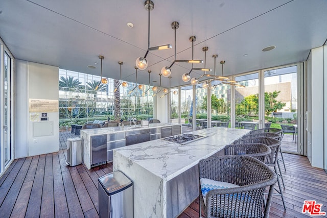 exterior space with light stone counters, a center island, decorative light fixtures, dark hardwood / wood-style flooring, and expansive windows