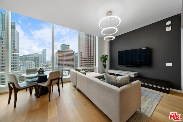 living room featuring a wall of windows, light wood-type flooring, and an inviting chandelier