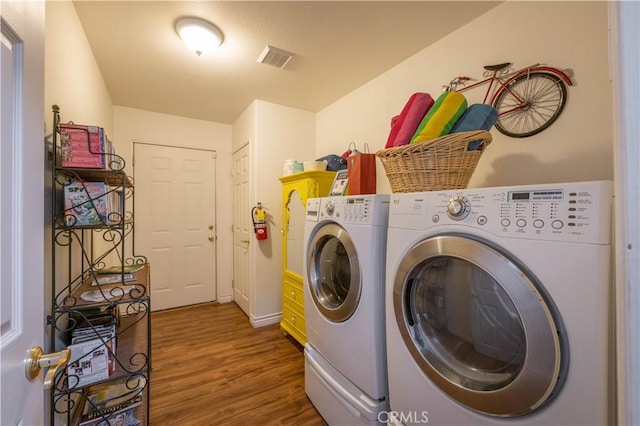 clothes washing area featuring washing machine and clothes dryer and dark hardwood / wood-style flooring