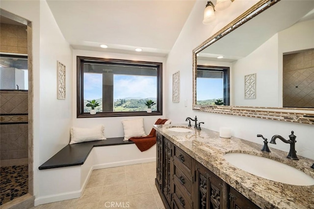 bathroom with tile patterned flooring, vanity, and tiled shower