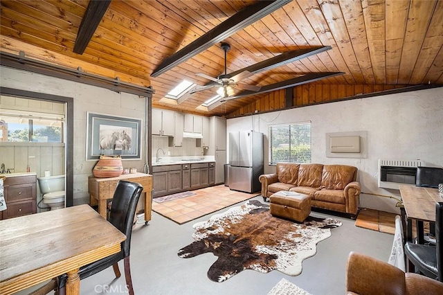 living room featuring ceiling fan, vaulted ceiling with skylight, heating unit, and wooden ceiling