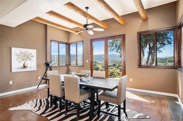 dining room with french doors, concrete flooring, a mountain view, beamed ceiling, and ceiling fan