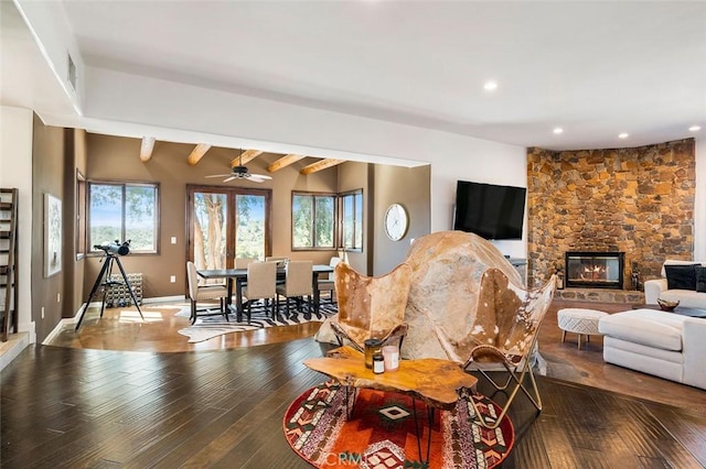 living room featuring beamed ceiling, hardwood / wood-style floors, a fireplace, and ceiling fan