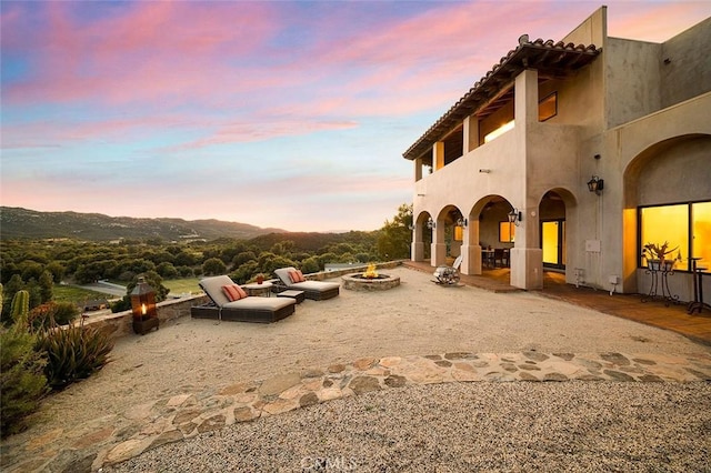 exterior space with a patio, a balcony, and an outdoor fire pit