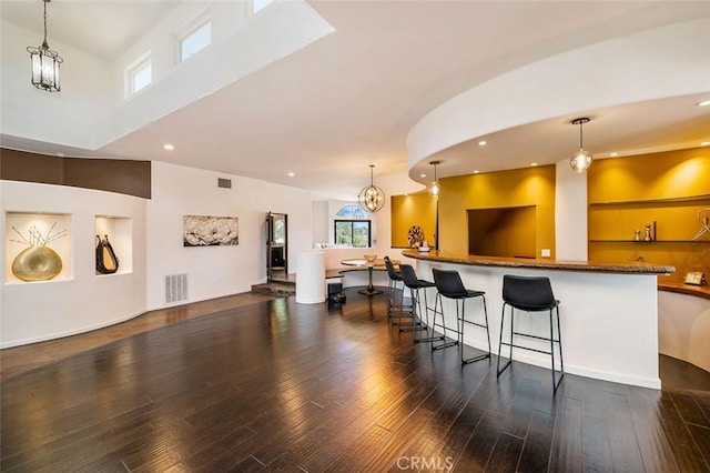 kitchen with a breakfast bar, kitchen peninsula, dark hardwood / wood-style floors, and decorative light fixtures