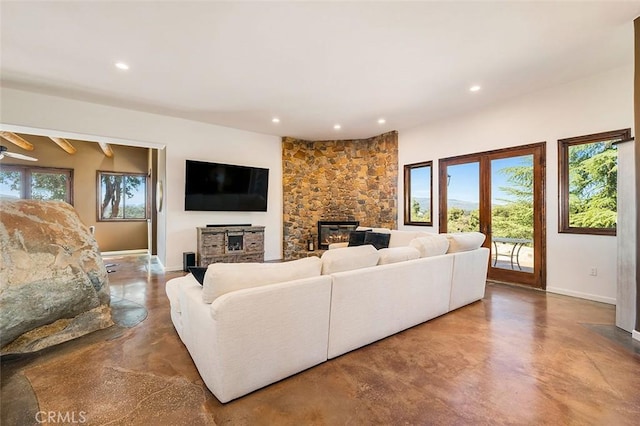 living room with concrete floors, ceiling fan, and a wood stove