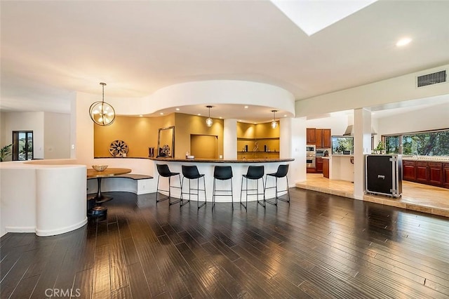 kitchen with an inviting chandelier, wood-type flooring, and a kitchen breakfast bar