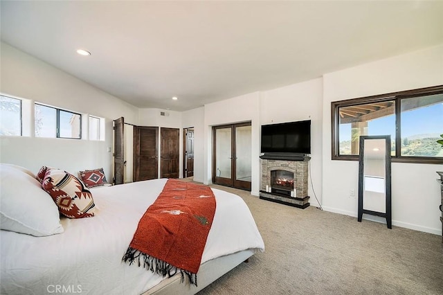 bedroom with multiple windows, carpet floors, a fireplace, and french doors