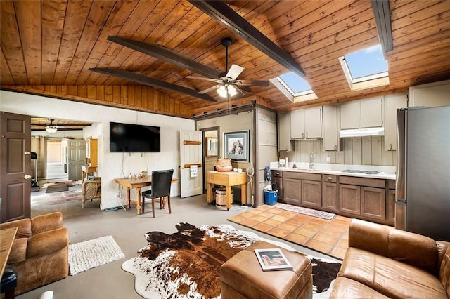 living room featuring ceiling fan, sink, vaulted ceiling with skylight, and wood ceiling