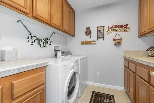 clothes washing area with cabinets and washer and clothes dryer