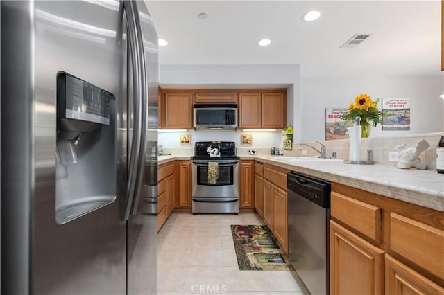 kitchen featuring light tile patterned floors, stainless steel appliances, and sink