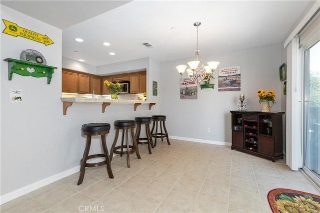 kitchen featuring an inviting chandelier, pendant lighting, a kitchen breakfast bar, and kitchen peninsula