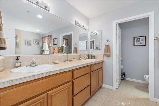 bathroom featuring double vanity, a sink, baseboards, and toilet
