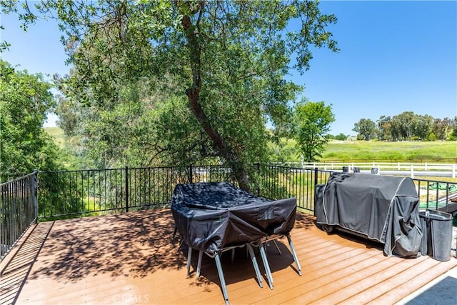 wooden deck with a rural view and a grill