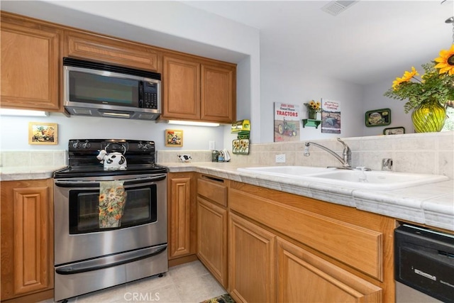 kitchen with stainless steel appliances, sink, and light tile patterned floors