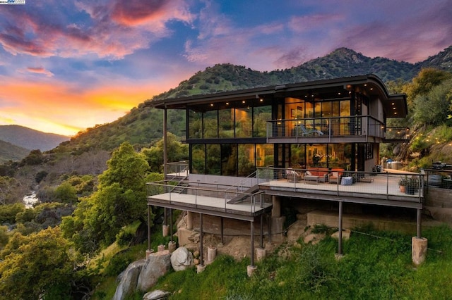 back house at dusk with a balcony and a mountain view