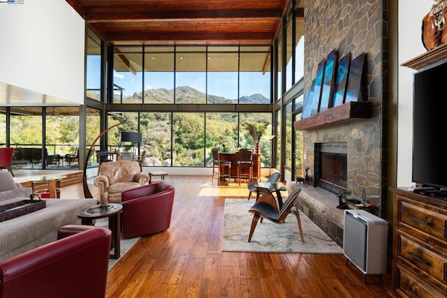 living room featuring a fireplace, a towering ceiling, hardwood / wood-style floors, and wood ceiling