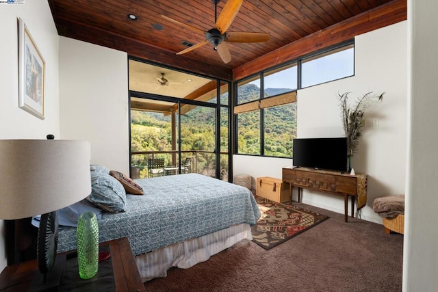 carpeted bedroom with multiple windows, beamed ceiling, ceiling fan, and wooden ceiling