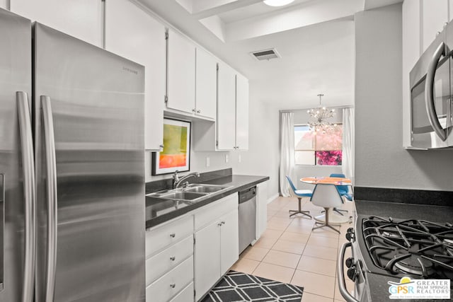 kitchen with white cabinets, sink, light tile patterned floors, appliances with stainless steel finishes, and an inviting chandelier