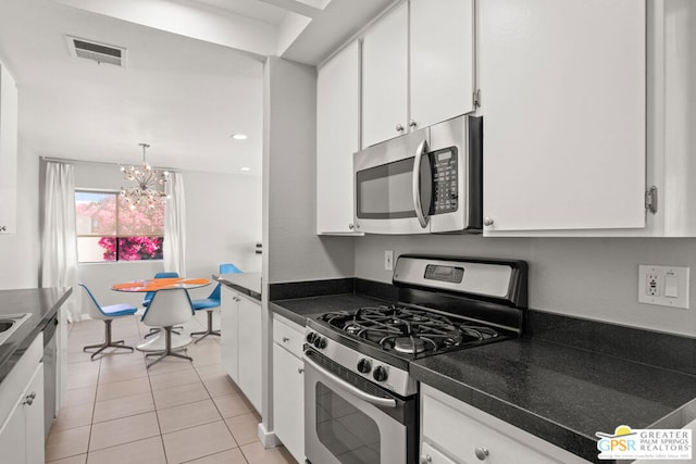 kitchen with white cabinets, an inviting chandelier, appliances with stainless steel finishes, and light tile patterned floors