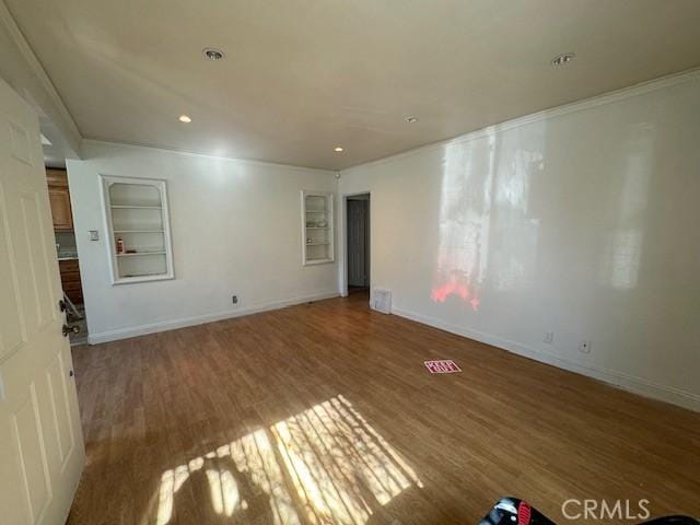 unfurnished room with built in shelves and wood-type flooring