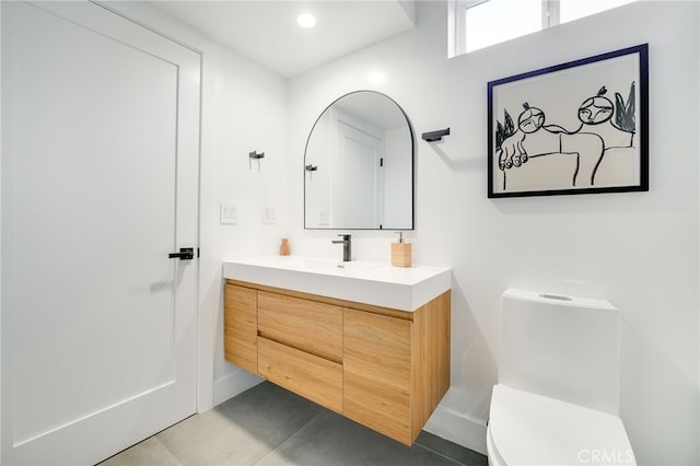 bathroom with toilet, vanity, and tile patterned flooring