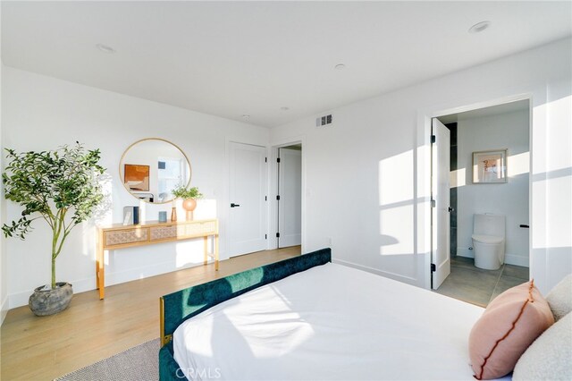 bedroom featuring ensuite bath and light hardwood / wood-style floors