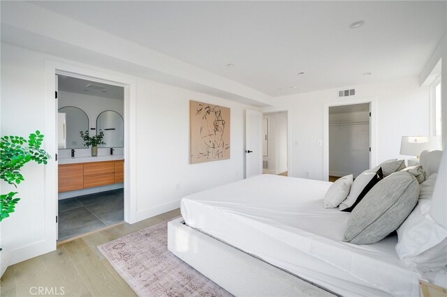 bedroom featuring a spacious closet and light hardwood / wood-style floors