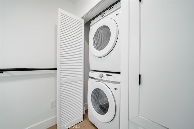 laundry area featuring light hardwood / wood-style flooring and stacked washing maching and dryer