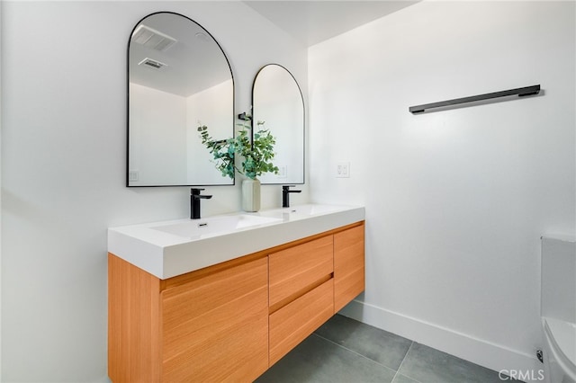 bathroom featuring dual vanity, toilet, and tile patterned flooring