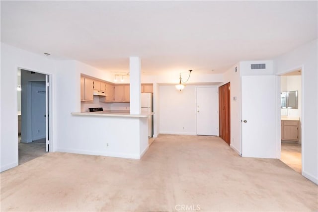 kitchen featuring kitchen peninsula, light colored carpet, decorative light fixtures, and white refrigerator