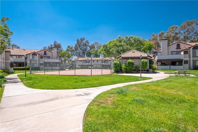 view of property's community featuring a yard and tennis court