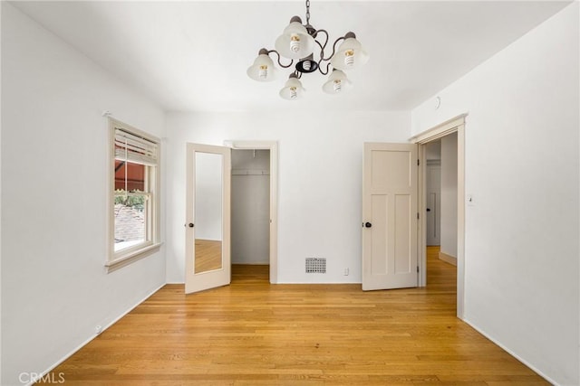 unfurnished bedroom featuring light hardwood / wood-style floors, a closet, and a chandelier