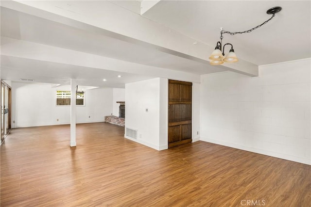 basement with a chandelier, hardwood / wood-style flooring, and a brick fireplace