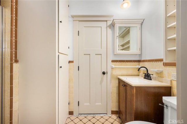 bathroom featuring vanity, tile walls, and toilet