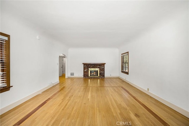 unfurnished living room with a brick fireplace and light wood-type flooring