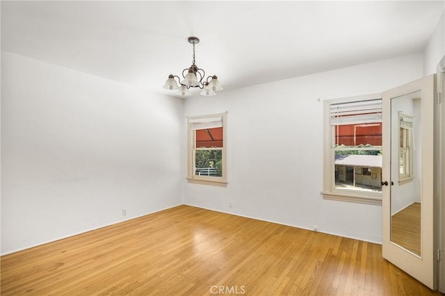 unfurnished room with hardwood / wood-style floors and an inviting chandelier