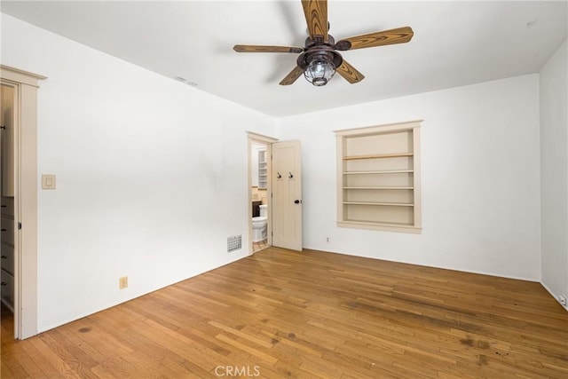 spare room featuring hardwood / wood-style floors, ceiling fan, and built in shelves