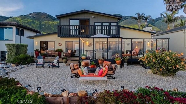 back of house featuring outdoor lounge area, a mountain view, a balcony, and a patio