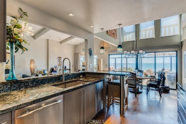 kitchen featuring dishwasher, dark hardwood / wood-style flooring, dark stone counters, decorative light fixtures, and a water view