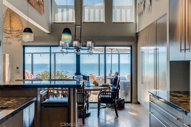 kitchen featuring dark stone countertops, plenty of natural light, a water view, and pendant lighting