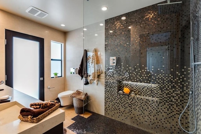 bathroom with toilet, tile patterned flooring, and tiled shower