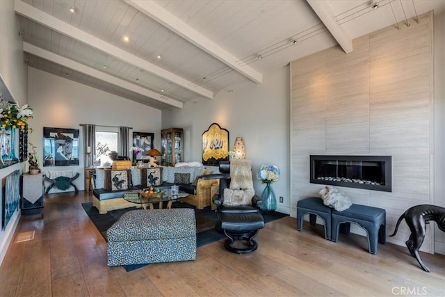 living room with beamed ceiling, wood-type flooring, a fireplace, and high vaulted ceiling