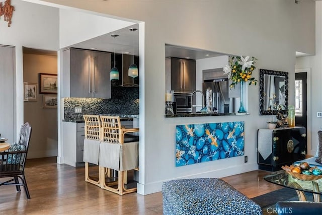 kitchen featuring hardwood / wood-style flooring, backsplash, wall chimney range hood, and stainless steel appliances