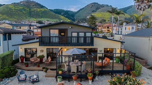 back of property with a deck with mountain view and a balcony