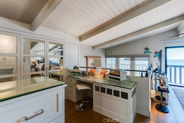 kitchen featuring white cabinets, vaulted ceiling with beams, dark wood-type flooring, and a breakfast bar