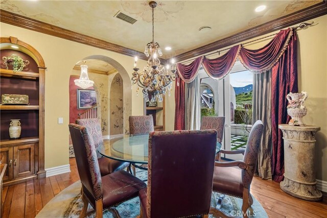 dining space with a notable chandelier, ornamental molding, and hardwood / wood-style floors